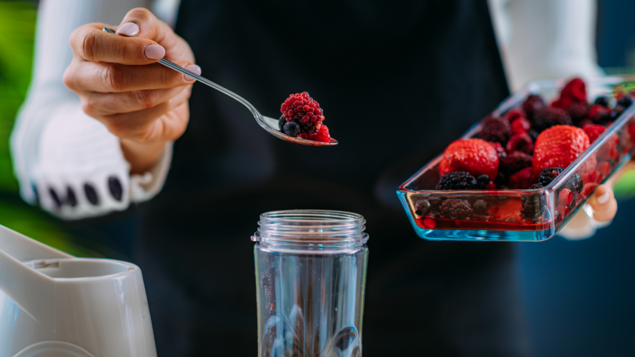 Gospođa u blender dodaje bobice voća