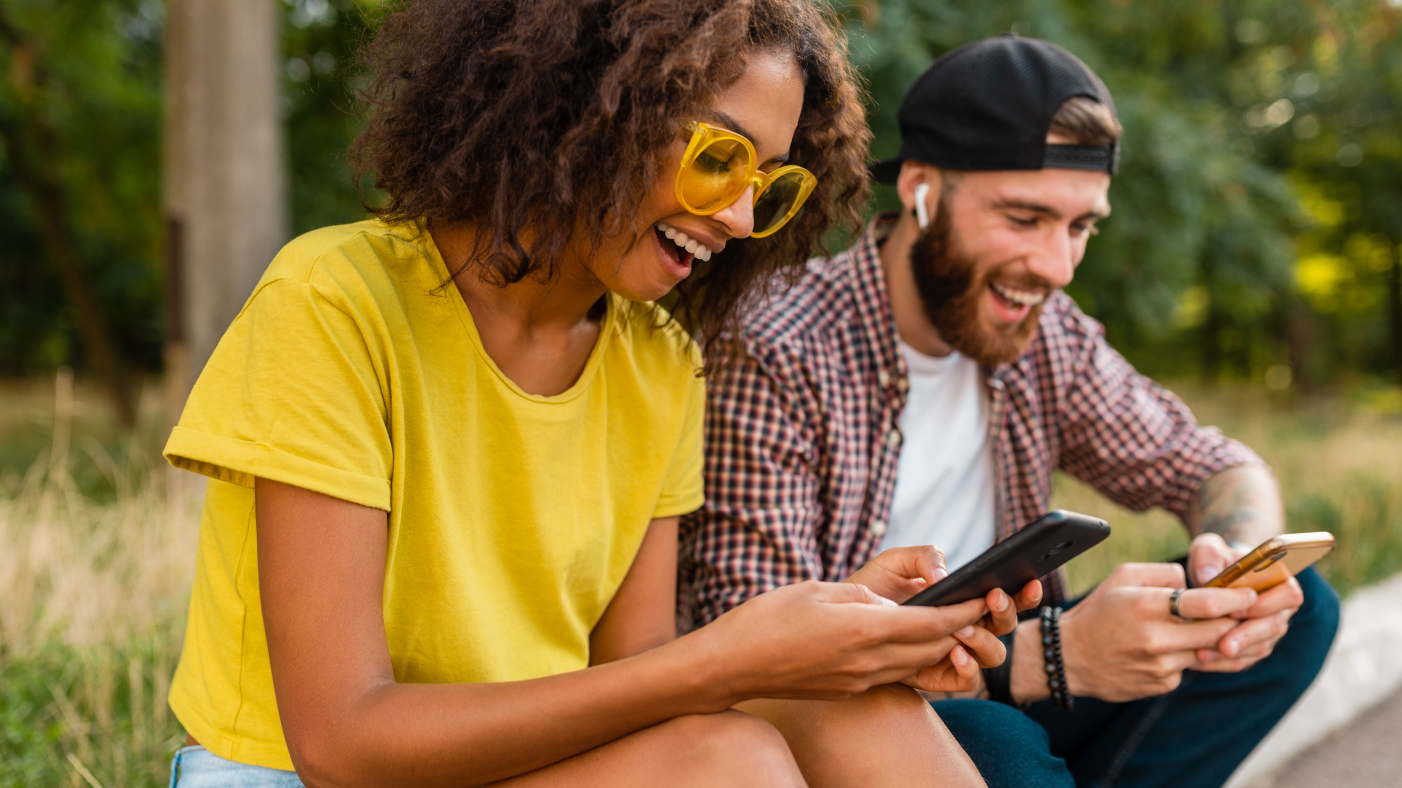 Man and women smiling and watching at their phones